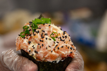 Temaki Sushi delicioso com salmão com cebolinha na mão do cozinheiro. Cozinha japonesa tradicional