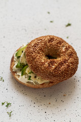 A bagel with cream cheese, avocado, blue cheese and microgreen