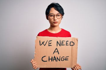 Beautiful asian girl protesting holding banner with change message over white background with a...