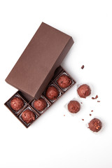 Round shaped chocolates with nuts in a rectangular box on a white background