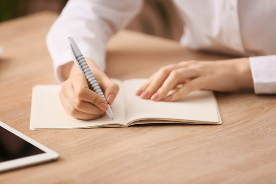 Woman writing something in notebook at table