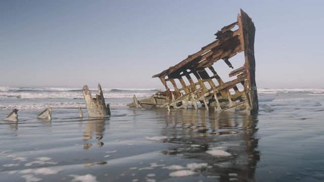 Peter Iredale shipwreck at fort stevens state park astoria oregon ocean waves and blue sky on sandy beach close up tracking forward