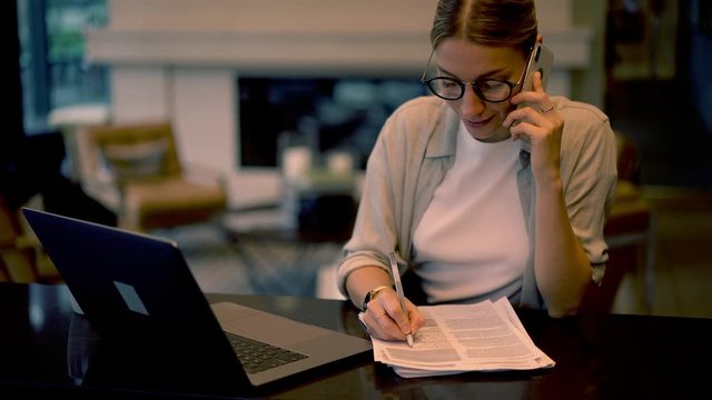 Female book editor in optical spectacles reading best seller outline and calling to literature writer for discussing fresh ideas using 4g wireless connection on modern smartphone device