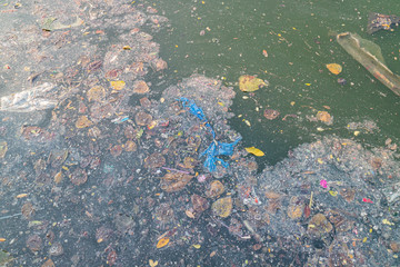 Grease and plastic waste floating on the surface of the water caused by the littering of urban areas causing pollution and flooding caused by clogging the drainage.