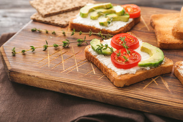 Board with tasty avocado sandwiches on table