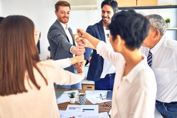 Group of business workers smiling happy. Standing bumping fists at the office