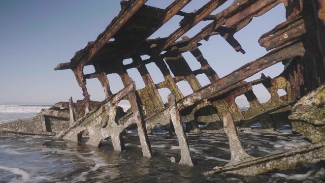 Peter Iredale rusty shipwreck at fort stevens state park astoria oregon ocean waves and blue sky on sandy beach close up reveal slow motion