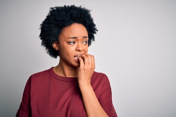 Fototapeta na wymiar Young beautiful African American afro woman with curly hair wearing casual t-shirt standing looking stressed and nervous with hands on mouth biting nails. Anxiety problem.