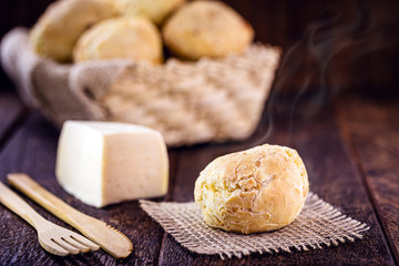 Brazilian cheese bread, on rustic wooden background with environmentally friendly bamboo cutlery.