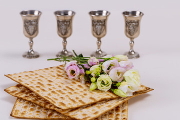 Jewish matzah bread on white background with four wine cups. Passover holiday concept