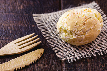 Brazilian cheese bread, on rustic wooden background with environmentally friendly bamboo cutlery.