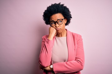 Young beautiful African American afro businesswoman with curly hair wearing pink jacket thinking looking tired and bored with depression problems with crossed arms.