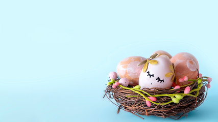 Wicker nest, basket with pink golden decorated eggs isolated on blue background. Ester banner greeting card, promotion flyer. Copy space, front view, vibrant colours