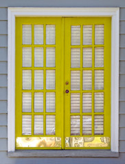 Newly yellow painted exterior double French doors with shiny metal base plate.