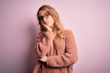 Young beautiful blonde woman wearing casual sweater and glasses over pink background thinking looking tired and bored with depression problems with crossed arms.