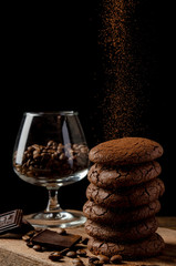 Coffee and chocolate cookies with coffee beans and chocolate on the dark background. Sprinkle cacao.