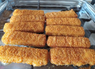 Cod sticks, breaded, close up. Cooked fish fingers baked in a glass oven-tray.