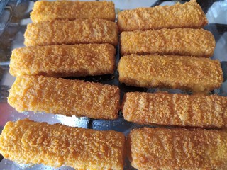 Cod sticks, breaded, close up. Cooked fish fingers baked in a glass oven-tray.