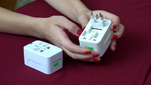 Beautiful hands of girl showing how to use universal electric socket plug adapters for travel. Used to connect to different electrical outlets worldwide. 4K.