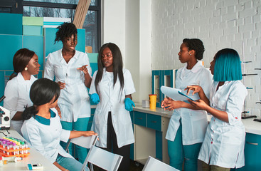 Female African medical students, young graduates or doctors discuss ongoing project. Energetic...