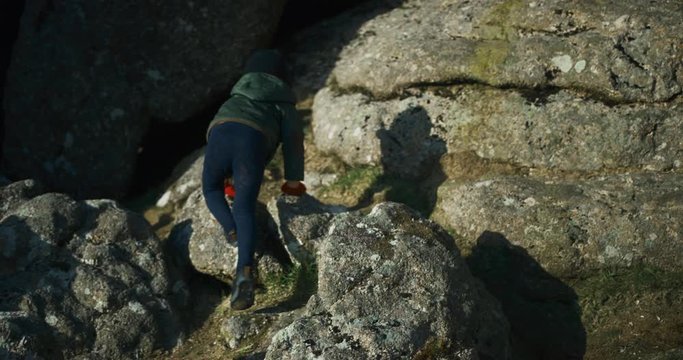 Little preschooler climbing rocks on the moor in winter