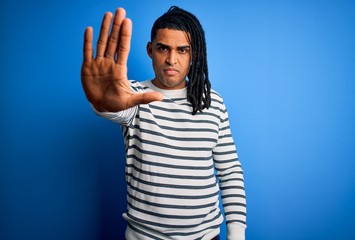 Young handsome african american afro man with dreadlocks wearing casual striped sweater doing stop...