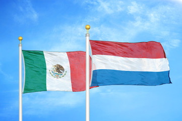Mexico and Netherlands two flags on flagpoles and blue cloudy sky