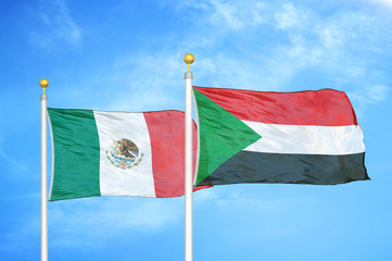 Mexico and Sudan two flags on flagpoles and blue cloudy sky