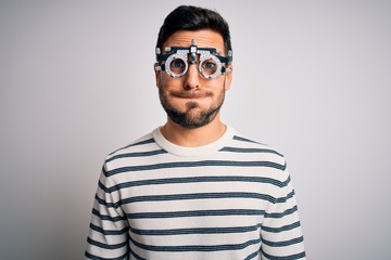 Young handsome man with beard wearing optometry glasses over isolated white background puffing...