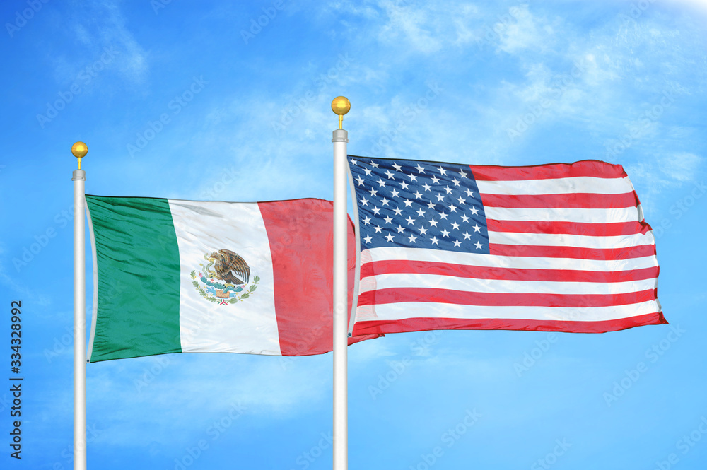 Wall mural mexico and united states two flags on flagpoles and blue cloudy sky - Wall murals