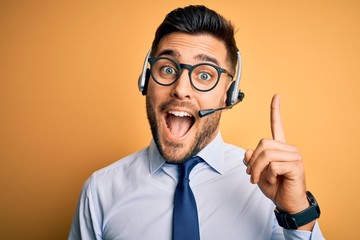 Young business operator man wearing customer service headset from call center pointing finger up...