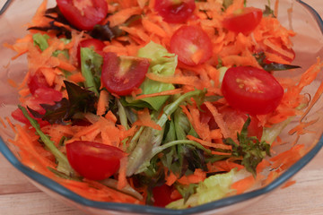 Salad bowl with tomato, carrots and leaves