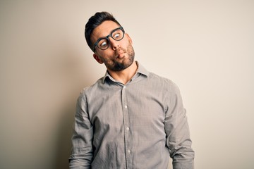 Young handsome man wearing elegant shirt and glasses over isolated white background making fish face with lips, crazy and comical gesture. Funny expression.