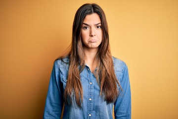 Obraz premium Young beautiful girl wearing casual denim shirt standing over isolated yellow background depressed and worry for distress, crying angry and afraid. Sad expression.