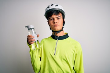 Young handsome cyclist man wearing security bike helmet drinking bottle of water with a confident expression on smart face thinking serious