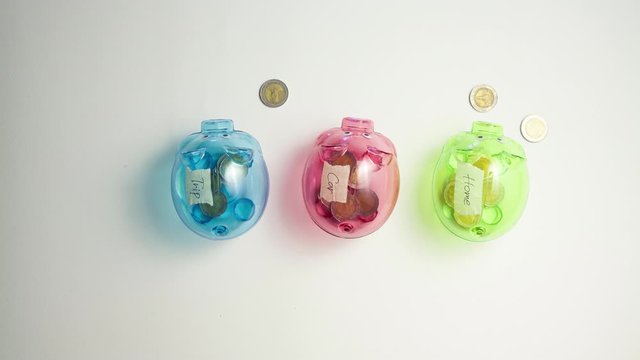 3 piggy bank piggy bank, 3 colors, green, pink, and blue, walking straight in to the center of the pictures There are coins arranged in a circle around the piggy bank. All coins walked in a circle and