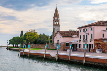 Fototapeta na wymiar Picturesque colorful houses and church tower in Burano island near Venice Italy with the view of the Venetian Lagoon
