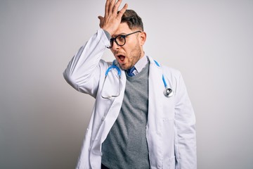 Young doctor man with blue eyes wearing medical coat and stethoscope over isolated background...
