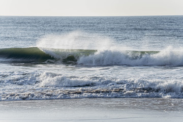 Atlantic Ocean beach with strong waves. Long Island New York shore. Blue sky with blue ocean. 
