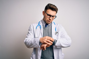 Young doctor man with blue eyes wearing medical coat and stethoscope over isolated background...