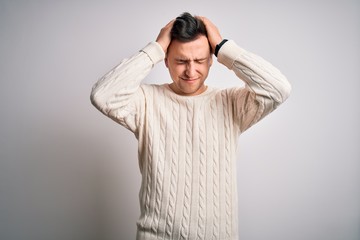 Young handsome caucasian man wearing casual winter sweater over white isolated background suffering from headache desperate and stressed because pain and migraine. Hands on head.