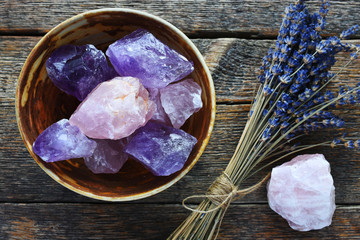 A table top image of a pottery bowl with large rose quartz and amethyst crystal with dried lavender...