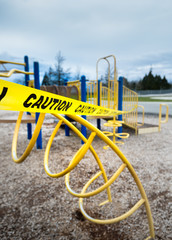 Yellow caution tape surrounding climbing apparatus in closed public playground during Coronavirus Covid-19 pandemic