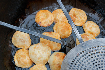 kachori being fried in a frying pan.