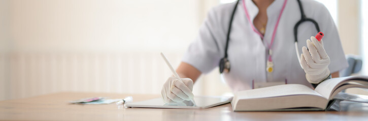 Close up view of female doctor reading book to analyse blood test
