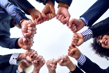 Group of business workers standing bumping fists at the office