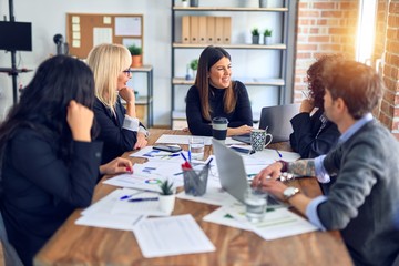 Group of business workers smiling happy and confident. Working together with smile on face  using laptop and speaking at the office