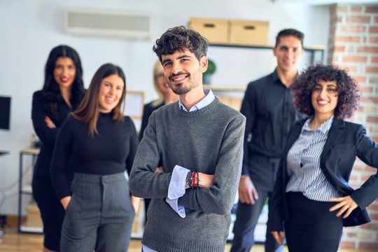 Group of business workers smiling happy and confident. Posing together with smile on face looking at the camera, young handsome man with crossed arms at the office