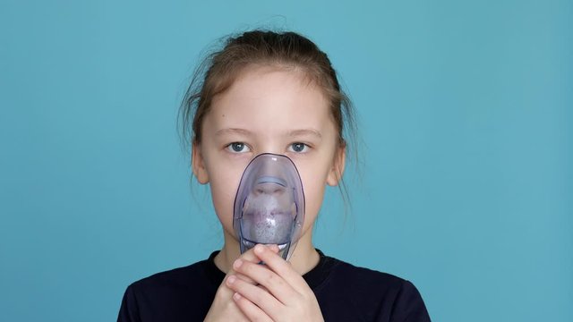 Portrait of child girl using nebulizer with breathing mask inhaling medication