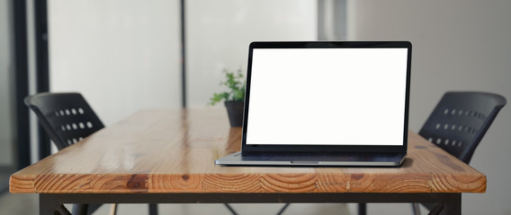 Close up view of mock-up laptop on wooden desk in co-working space